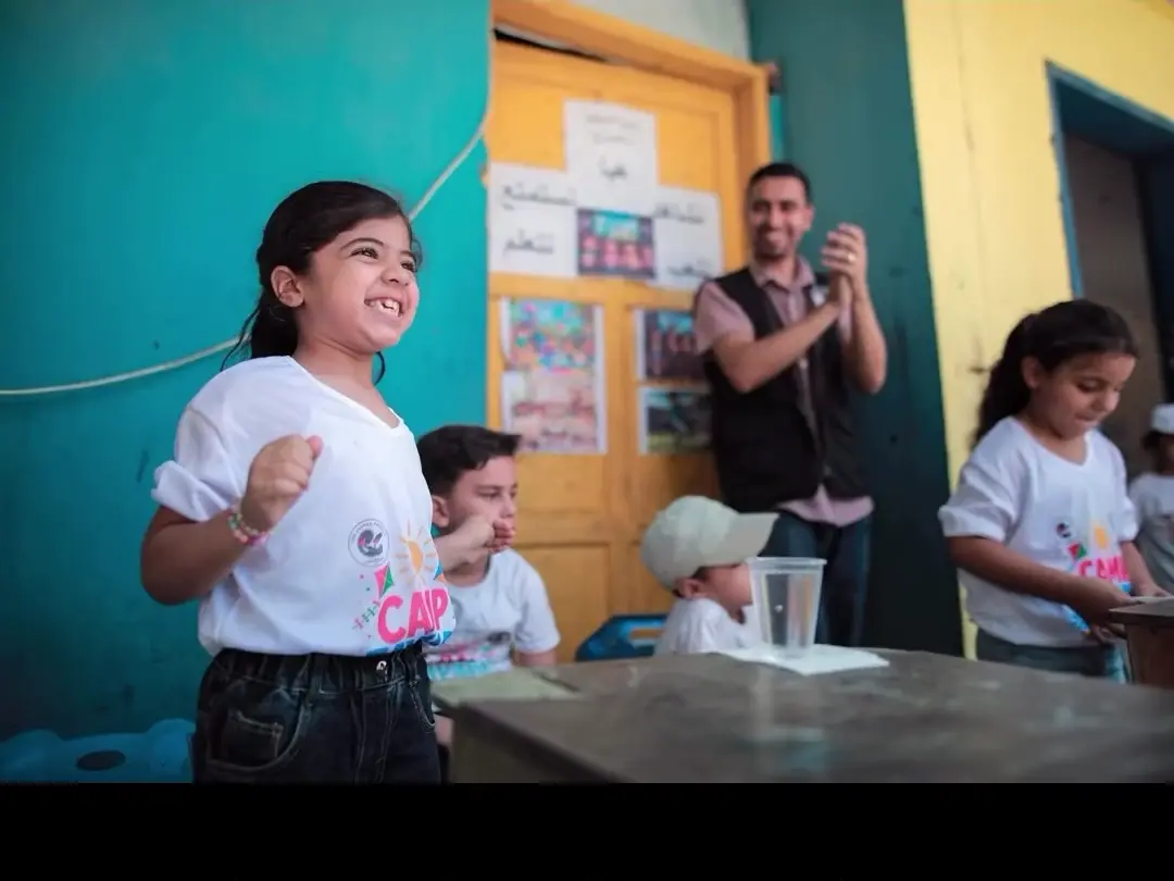 A child laughing while a facilitator remains visible during a Camp Zaynab activity