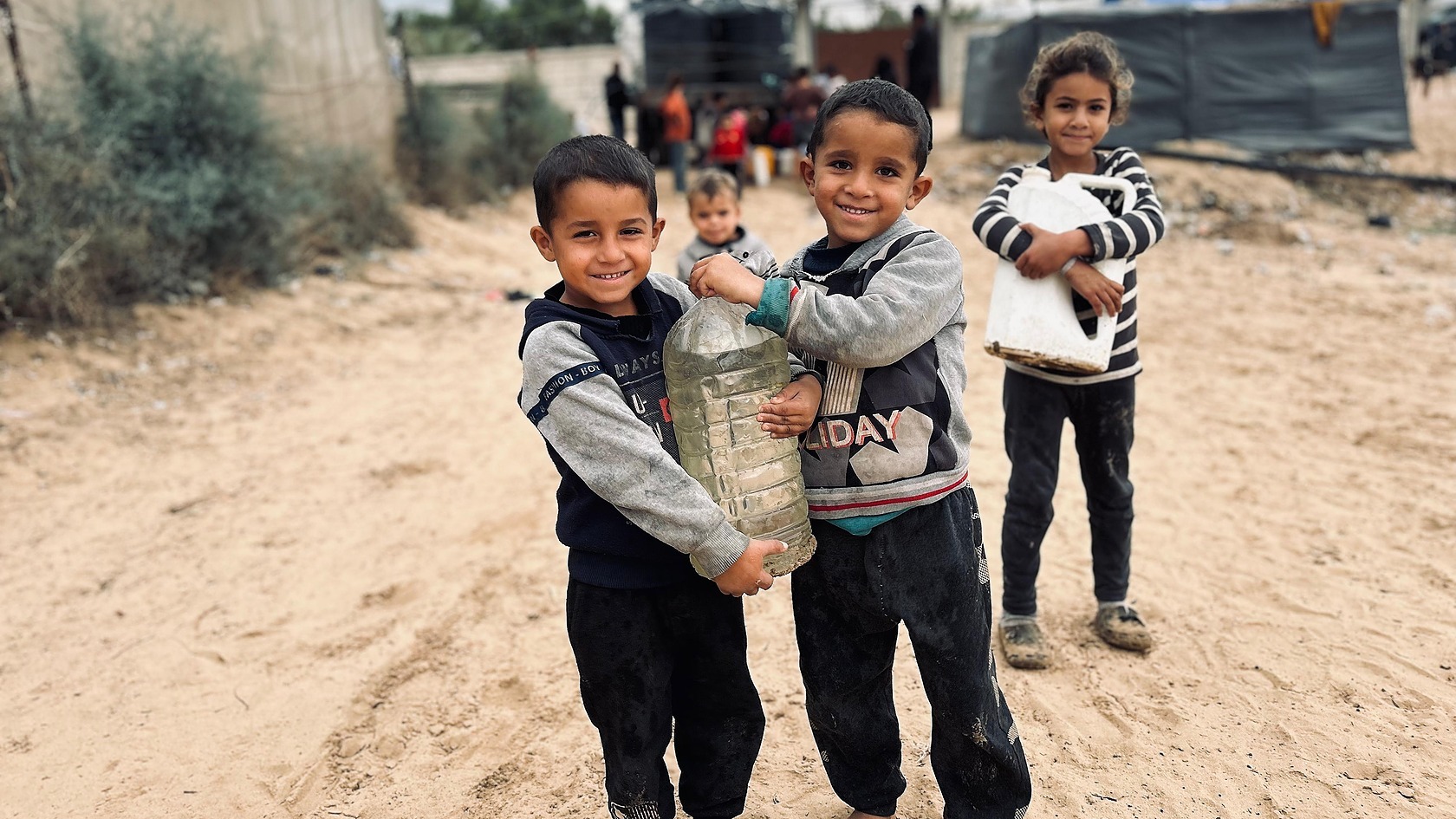 Children moving together through a camp lane in an official Zaynab Project campaign photograph