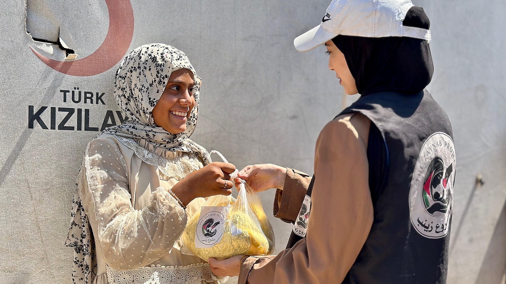 A Zaynab Project team member offering a bag to an older woman