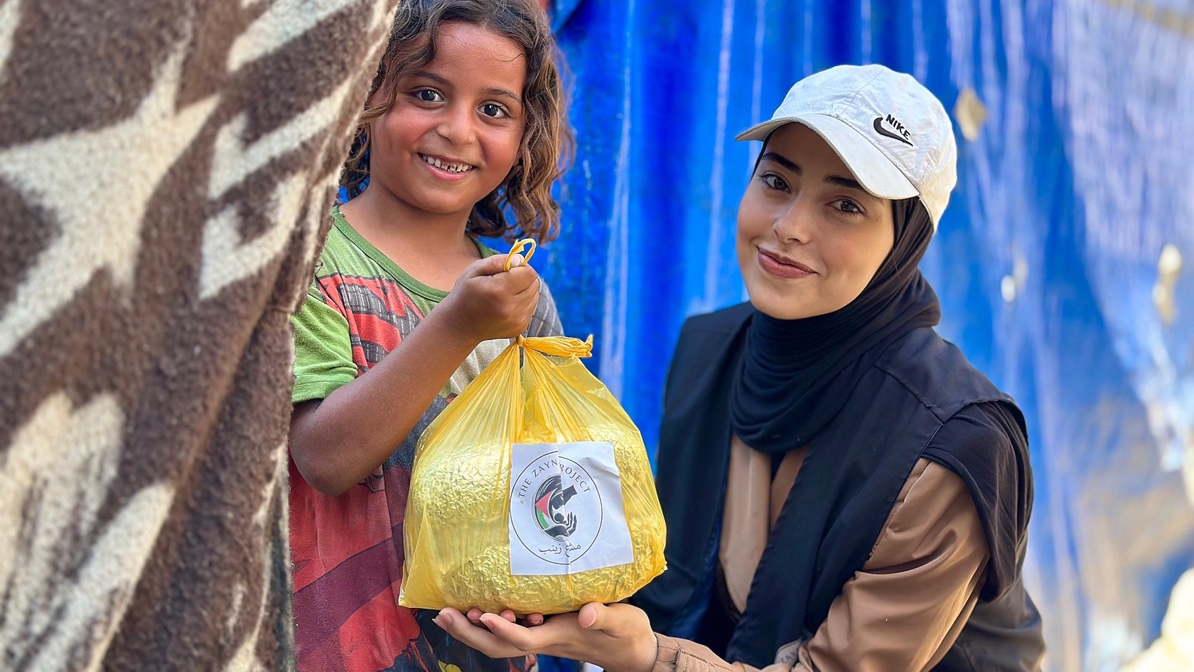 A woman from the Zaynab Project ground team standing beside a girl