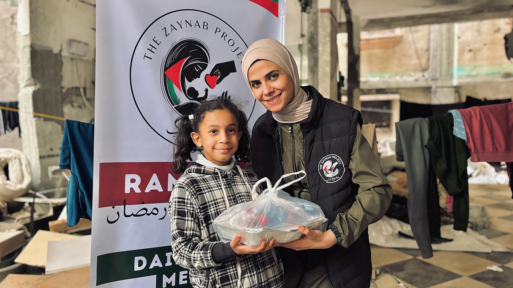 A woman from the Zaynab Project ground team standing beside a girl in an official campaign photograph