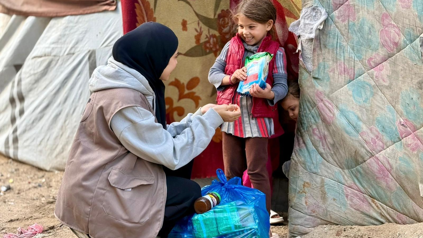 A Zaynab Project team member offering a toy to a girl in an official campaign photograph